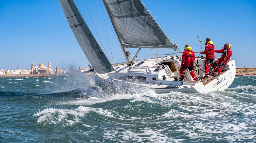 Velero trimando velas para soportar la fuerza del viento del nordeste y sus rachas de viento mar adentro.