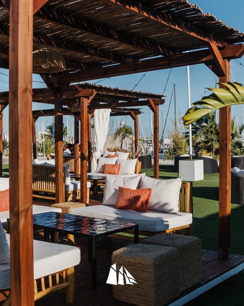 Reservas de Espacio Thai con pérgolas de madera y sofás frente a la marina de Puerto Sherry Cádiz.