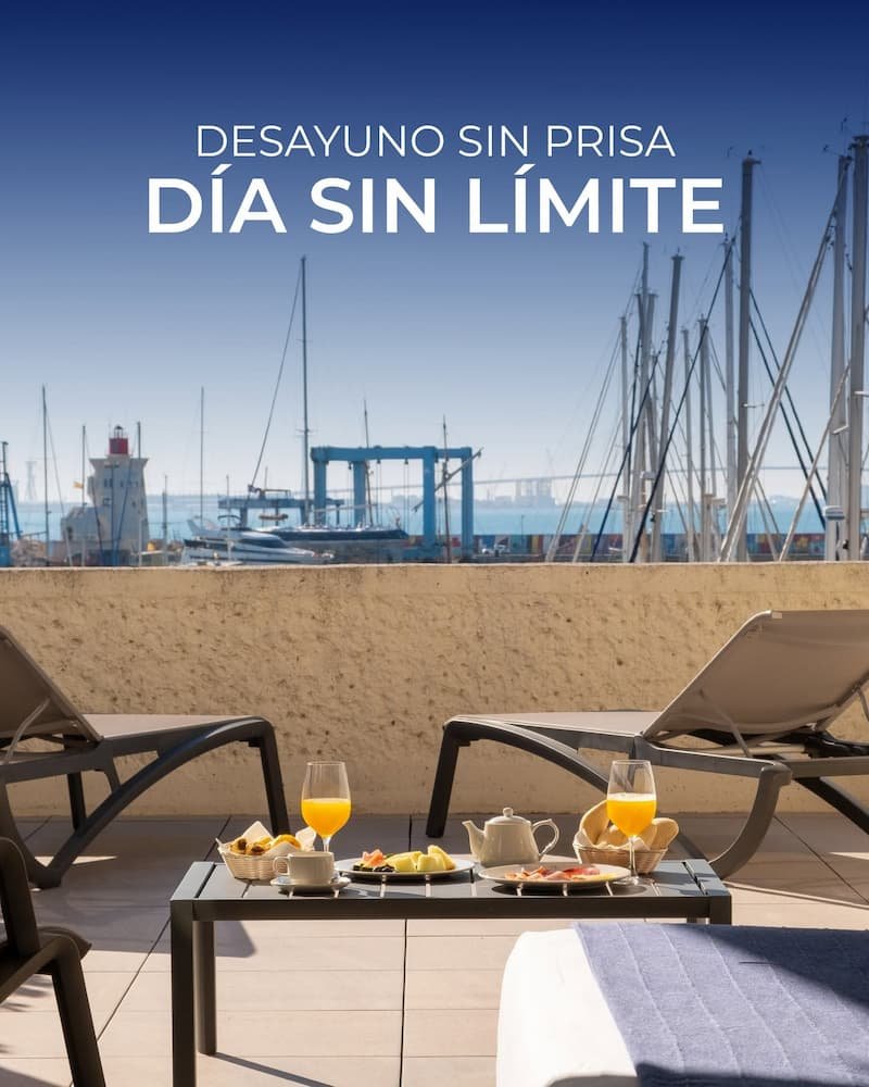 Desayuno con zumo y frutas en la terraza con tumbonas y vistas al mar del hotel Puerto Sherry en Cádiz.