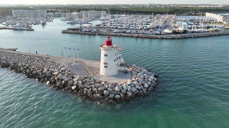 High-angle view from a glass balcony overlooking the Puerto Sherry marina filled with moored sailboats and yachts under a pastel sunset sky.